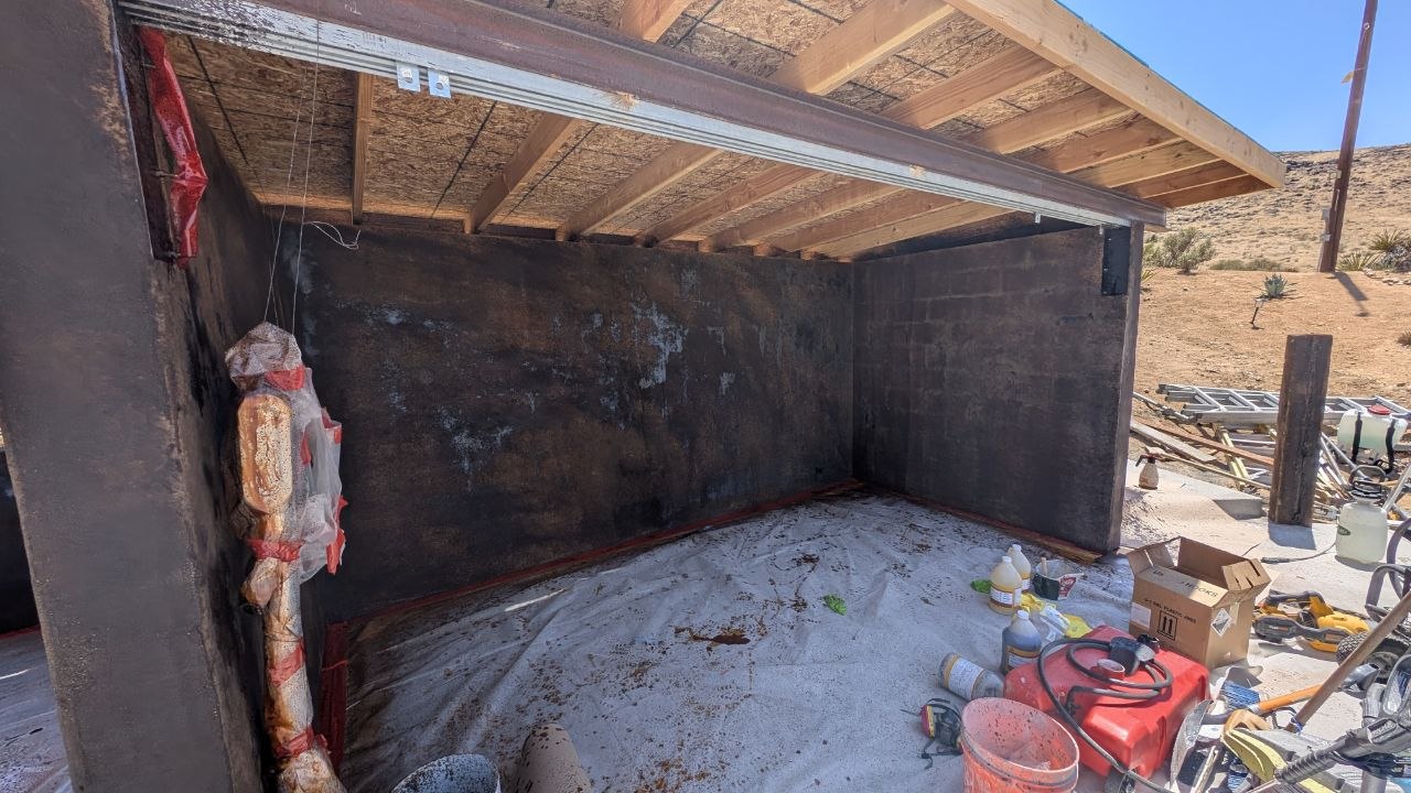 Interior of the shed showing wood beam framing and fresh stucco walls before finishing