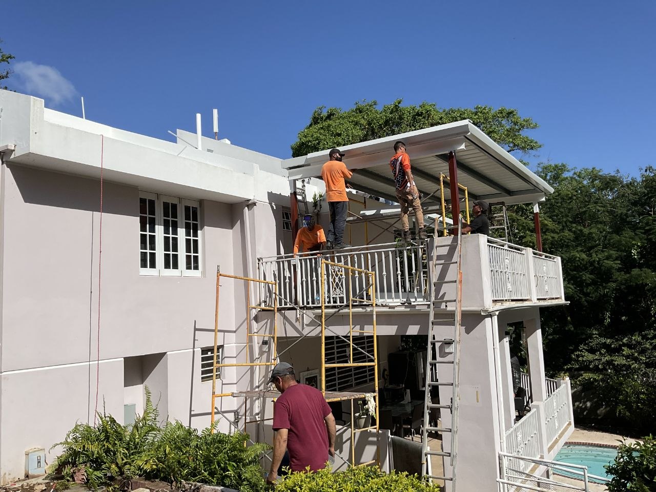 Crew constructing custom iron pergola on an outdoor deck