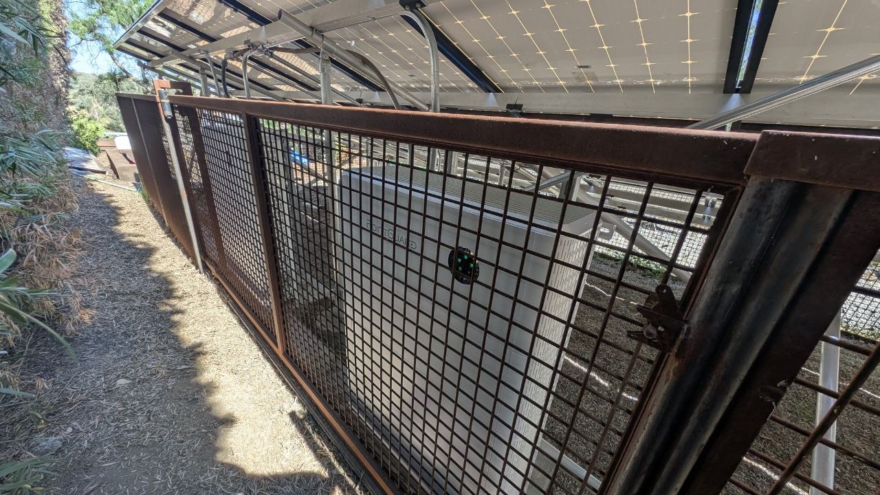 PointGuard battery unit visible through the steel mesh fence enclosure under the solar array